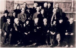 Wachenheimer Family, Camp de Gurs Internment Camp Inmates, some seated, most standing, are outside, in front of a wooden building.