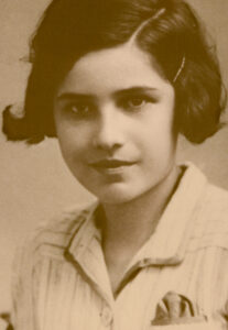 A black and white passport photo of a young girl with short dark hair looking straight ahead, slight smile