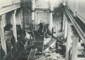Interior of synagogue destroyed during Kristallnacht, furniture and light fixtures broken and heaped in piles in the center of the floor
