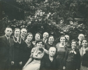 Hedy Epstein and twelve family members surrounding a seated elderly woman, Hedy's grandmother, in her backyard